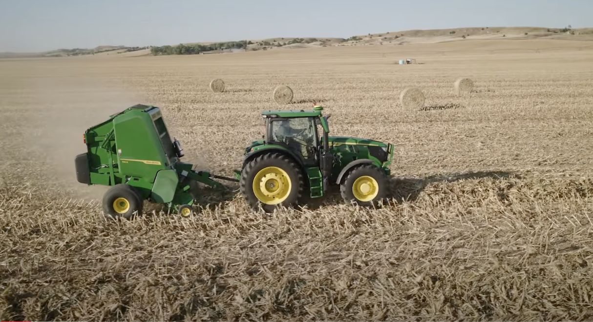 The John Deere 561R hay baler in action in a field.